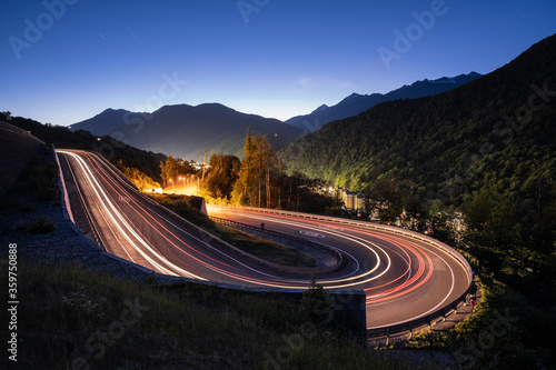 A winding road in the mountains. A trail from the car headlights. Mountains. Evening lighting.