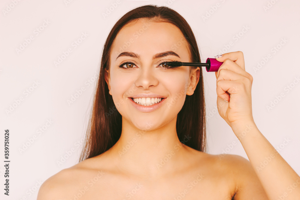 Portrait happy beautiful girl apply mascara cosmetics on long perfect eyelashes extension, smile isolated white background. Attractive young woman put mascara make up. Girl posing with mascara brush Portrait happy beautiful girl apply mascara cosmetics on long perfect eyelashes extension, smile isolated white background. Attractive young woman put mascara make up. Girl posing with mascara brush