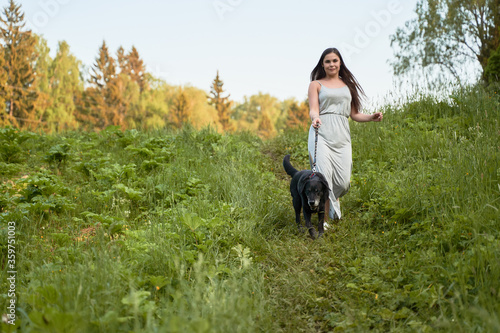 Brunette woman on walk with dog in park on summer