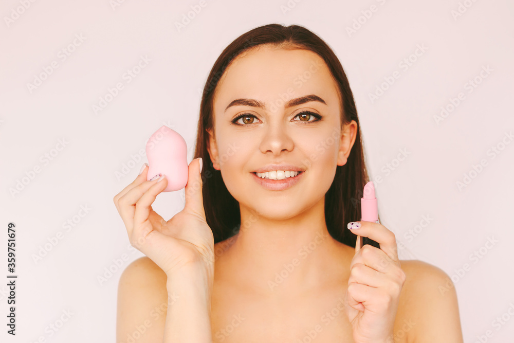Portrait beautiful cheerful woman with perfect skin posing with beauty blender pink lipstick in hands isolated white background. Young happy girl apply skin care make up cosmetics. Female beauty model Portrait beautiful cheerful woman with perfect skin posing with beauty blender pink lipstick in hands isolated white background. Young happy girl apply skin care make up cosmetics. Female beauty model