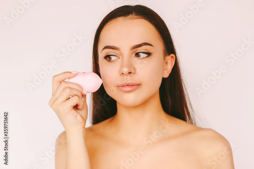 Portrait beautiful young woman apply make up of face with beauty blender and smile isolated white background. Attractive happy girl posing with make up sponge. Skin care cosmetics, female beauty model