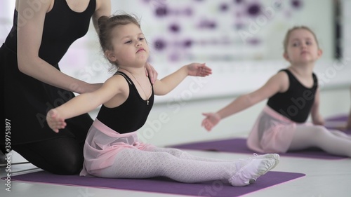 Little girl practices stretching in a modern ballerina school. Talented children. Modern cool ballet studios interior on the background.