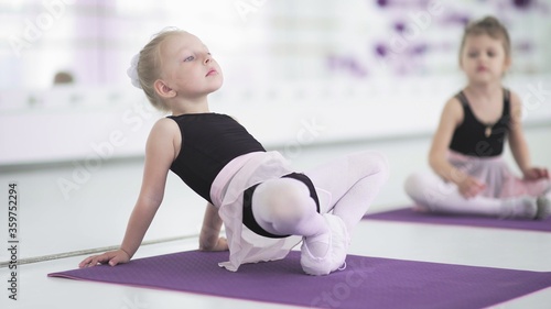 Little girls stretching and doing exercises in ballet school