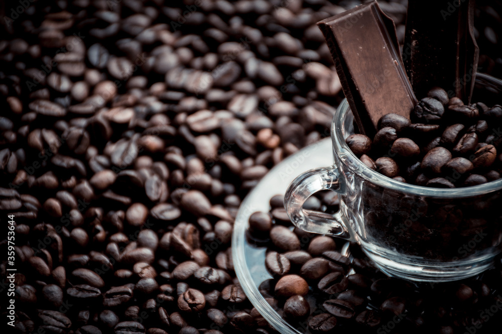 Fototapeta premium Coffee cup with saucer surrounded and filled up with coffee beans and chocolate inside the cup