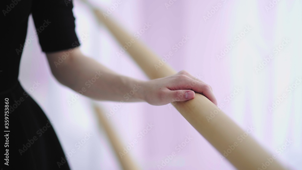 Close up of ballerinas hand on wooden barre