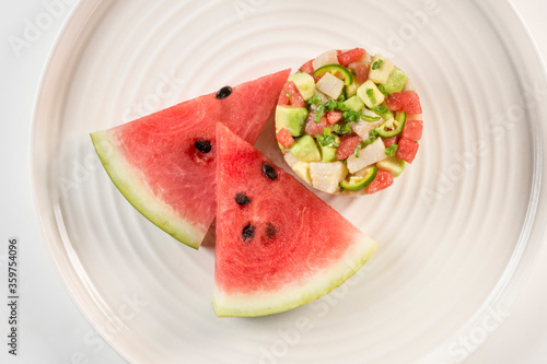 Ceviche cocktail in circle with watermelon wedges.
Elegant fish cocktail served in a round shape along fresh fruit.