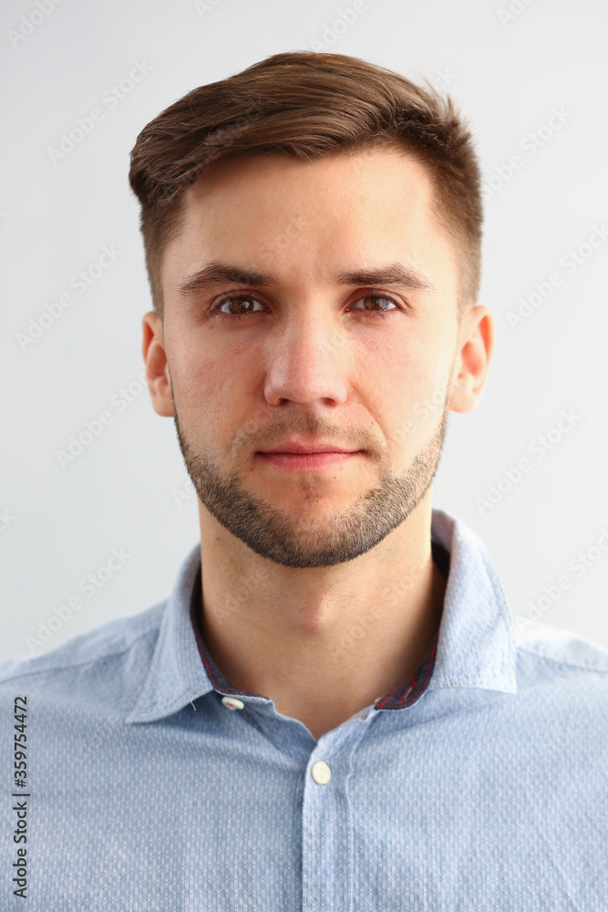 Close up of handsome gentleman in blue shirt looking at camera with serene expression Close up of handsome gentleman in blue shirt looking at camera with serene expression