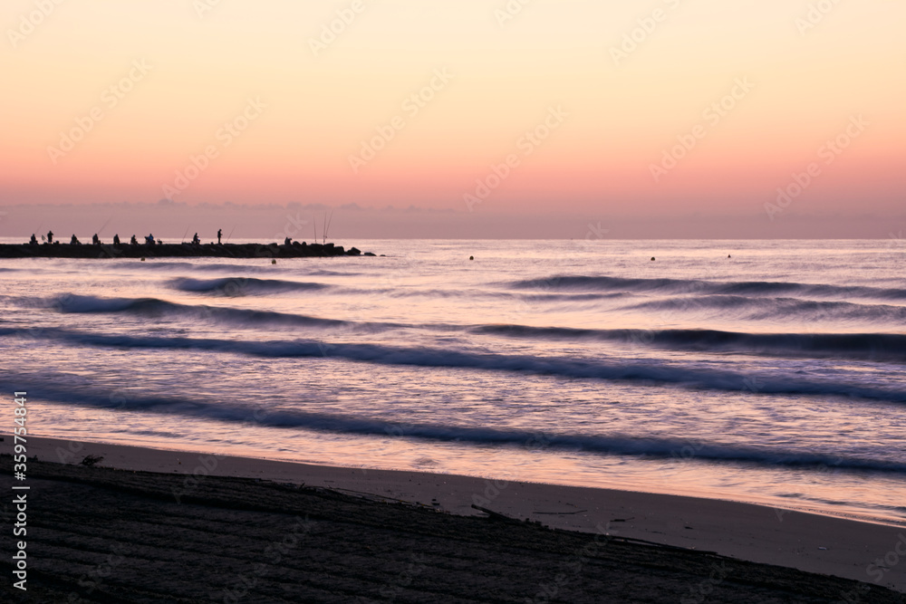 Sunrise on the beach, jetty with fishermen