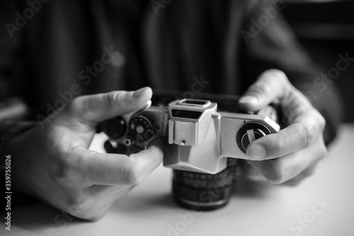 Man's hands set up a pentax retro film camera. Black and white