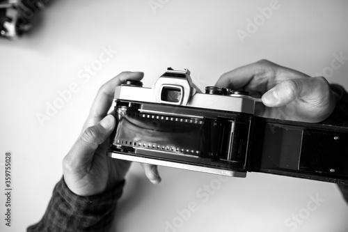 Male man hands reloads film in pentax retro camera on a white table photo