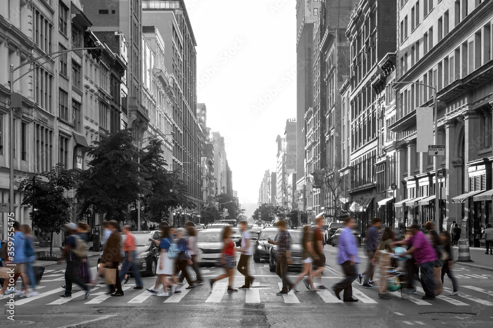 Colorful people walking across a busy intersection in a black and white Manhattan cityscape in New York City
