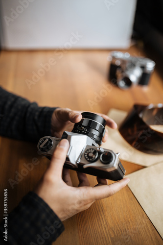 Male man hands adjusts the lens pentax retro camera on a white table
