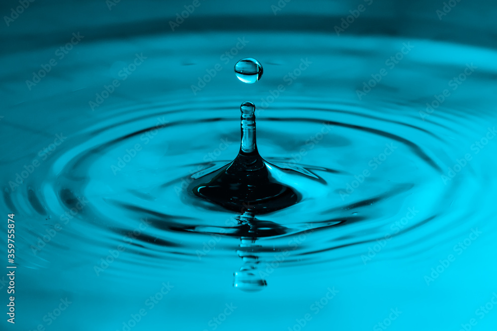 drop of water. Perfect water drop splashing into smooth water causing ripples