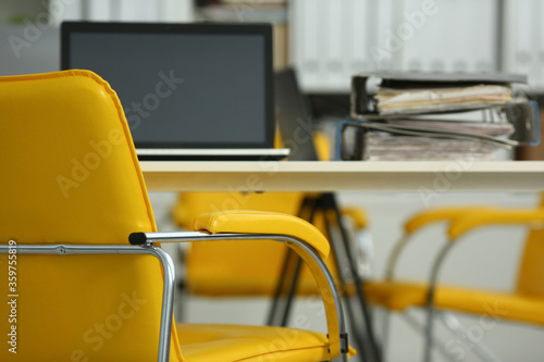 Close up of yellow office chair near desk with notebook and folders with papers