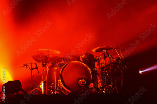 modern drum set on stage in red light at a music festival. concert poster of a popular rock band.