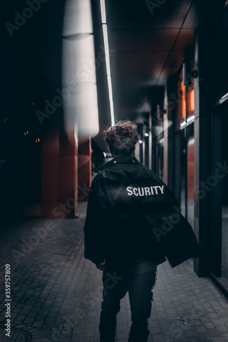 male with a security jacket walk in night street