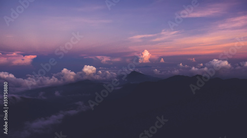 Aerial photo from airplane cockpit of an amazingly beautiful colorful sky with pink sunset over silhouette of mountains. Amazing landscape of a clouds with sundown in evening time. Perfect background