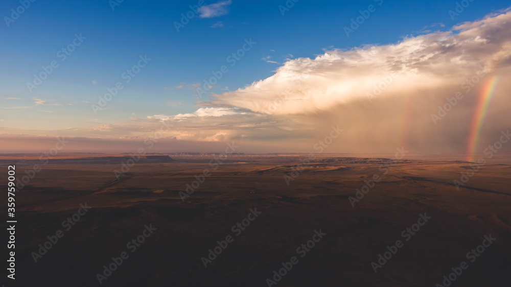 Aerial photo from flying drone of a beautiful nature landscape with field and amazing sky with dramatic clouds and colorful rainbows after raining weather. Wonderful scenery with steppe and skies