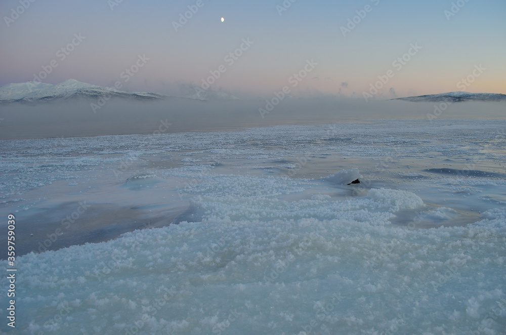 ice fog over fjord with thick ice, moonlight and colorful pink sunset sky ice fog over fjord with thick ice, moonlight and colorful pink sunset sky