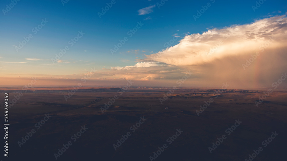 Aerial photo from flying drone of a beautiful nature landscape with wild field and amazing sky with dramatic colorful clouds. Wonderful scenery during steppe evening twitlight