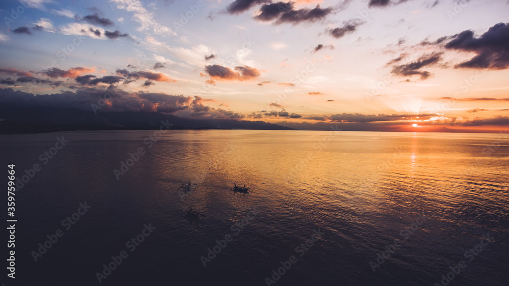 Aerial photo from flying drone of an amazing scenery of calm Indian Ocean with riding boats at sunset. Beautiful evening sky with sunset rays reflected in calm sea water  Wonderful nature wallpaper