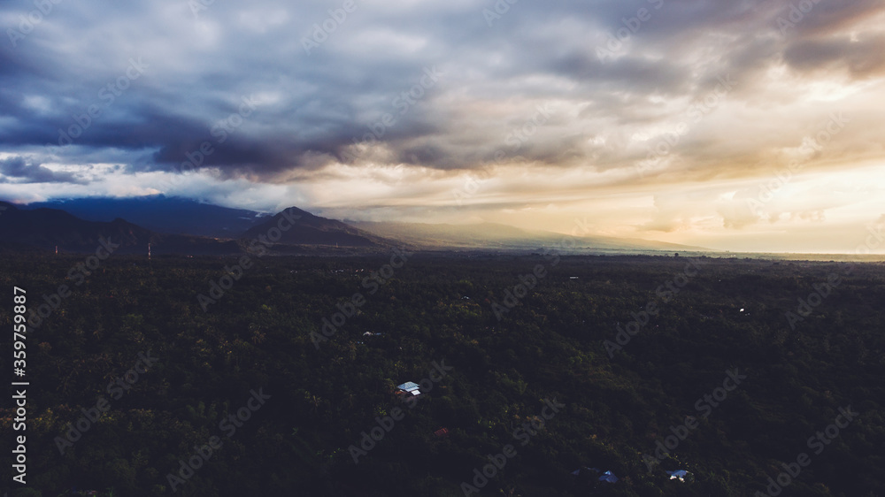 Aerial photo from airplane cockpit of a beautiful outdoors scenery with dramatic, white clouds with sunset rays over silhouette of mountains. Perfect background for website. Wonderful nature landscape