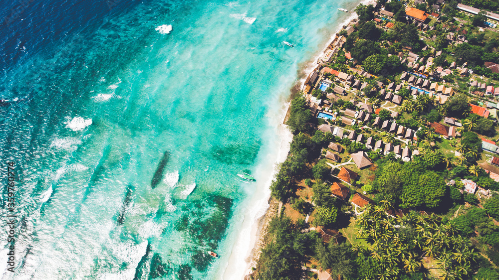 Top view aerial drone photo of stunning colored sea beach with crystalline water fringed with swaying tropical palms and leafy trees. Incredibly beautiful blue ocean meet with powder-white seashore
