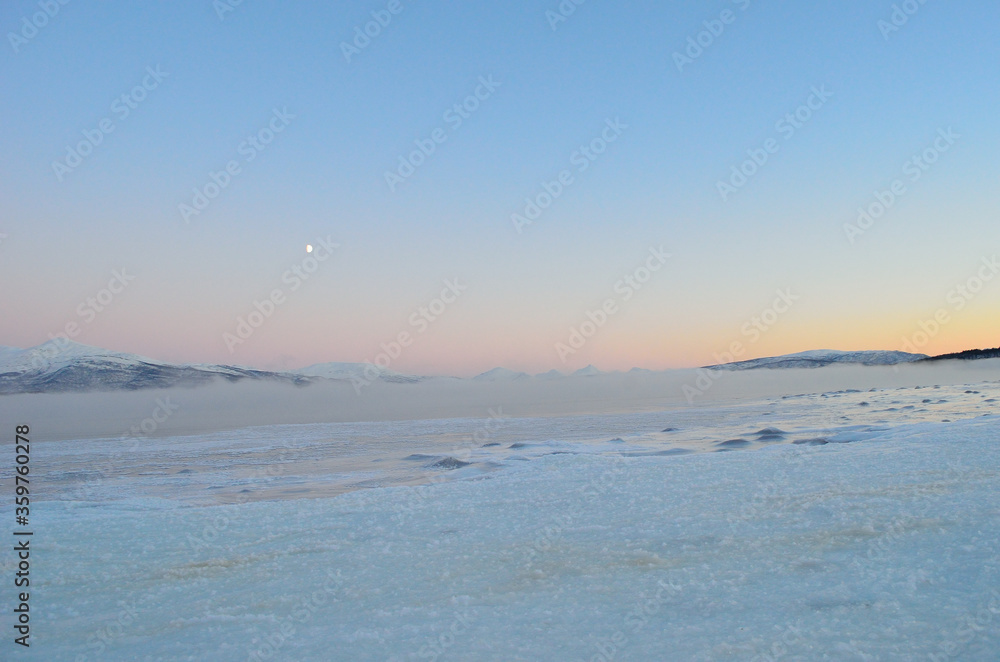 pink sunset sky and full moon over winter fjord with dense ice fog and reflection on water surface pink sunset sky and full moon over winter fjord with dense ice fog and reflection on water surface