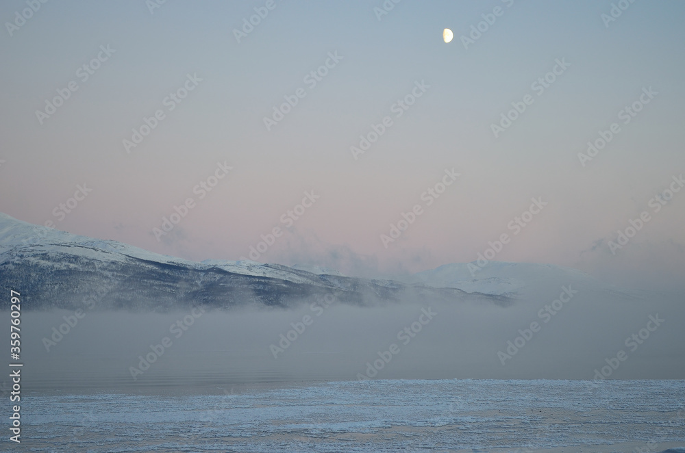 pink sunset sky and full moon over winter fjord with dense ice fog and reflection on water surface pink sunset sky and full moon over winter fjord with dense ice fog and reflection on water surface