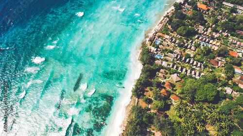 Top view aerial drone photo of stunning colored sea beach with crystalline water fringed with swaying tropical palms and leafy trees. Incredibly beautiful blue ocean meet with powder-white seashore
