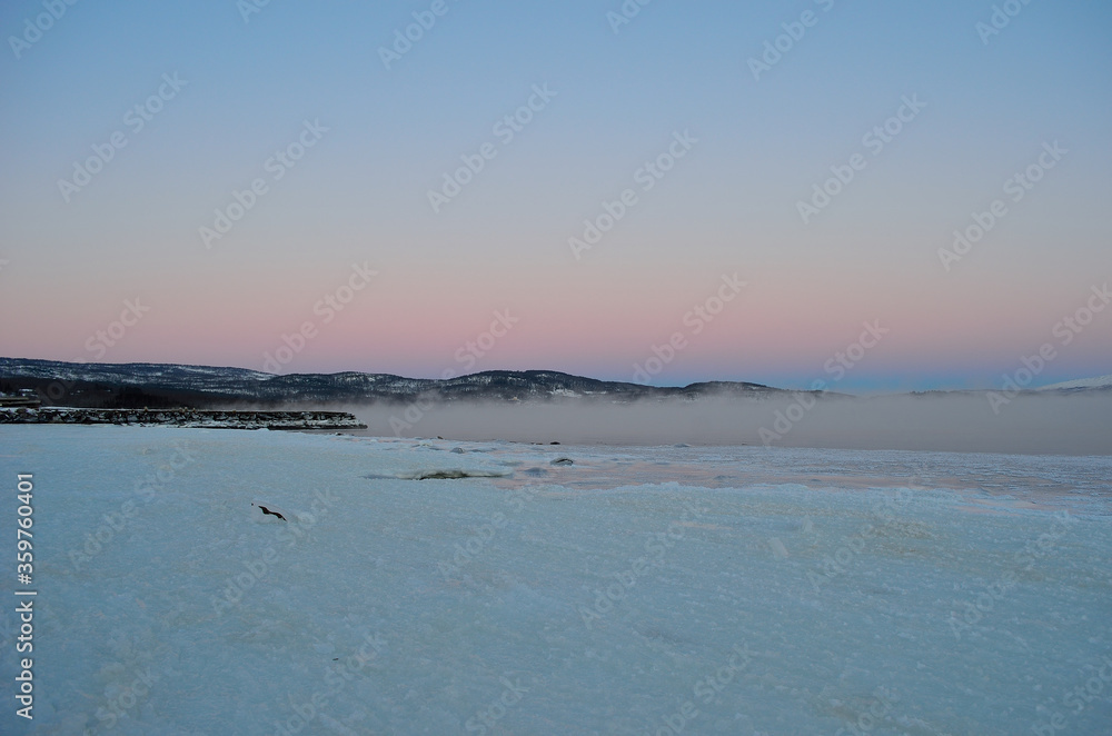 pink sunset sky in winter over frozen fjord and dense ice fog pink sunset sky in winter over frozen fjord and dense ice fog