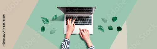 Person using a laptop computer with green leaves from above