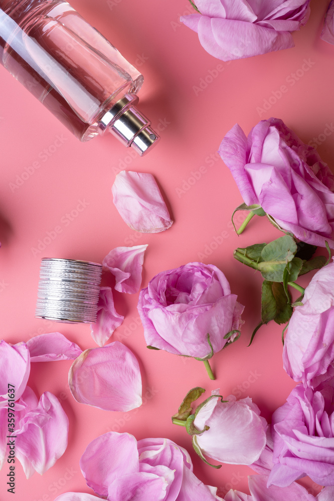 perfume bottle around may roses against pink background. beauty concept perfume bottle around may roses against pink background. beauty concept