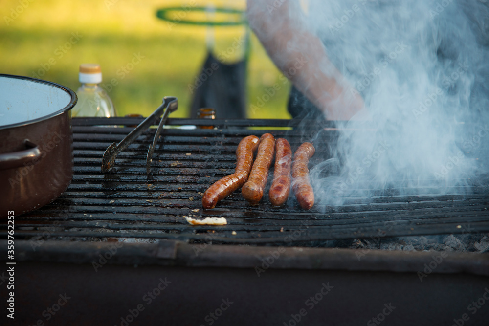 Grilling sausages outdoor on a gridiron over charcoal fire Grilling sausages outdoor on a gridiron over charcoal fire