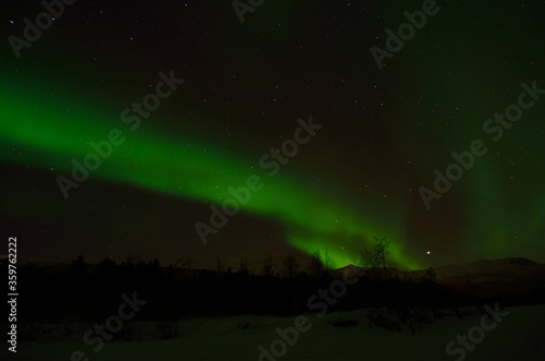 strong aurora borealis  northern light over frozen arctic circle landscape in winter night