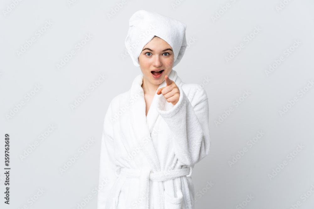 Teenager girl in a bathrobe isolated on white background surprised and pointing front Teenager girl in a bathrobe isolated on white background surprised and pointing front