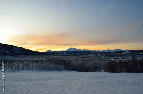 Scenic snowy mountain with vibrant colourful sky and white frost covered forest in the front © Arcticphotoworks