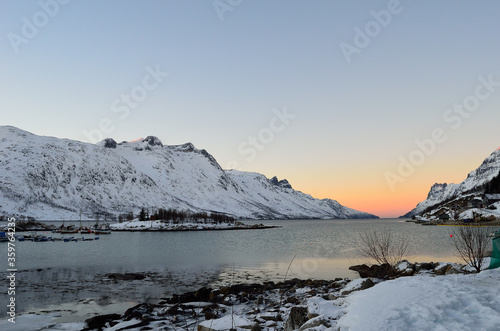 Dreamy vibrant colourufl dawn over fjord water with high snowy mountains in the arctic circle
