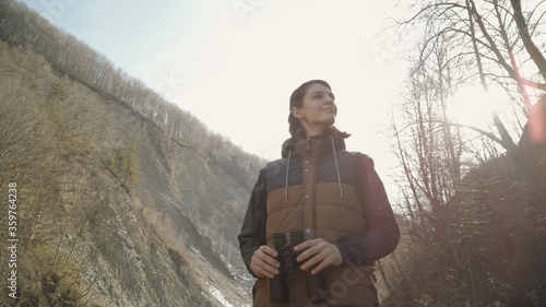 Woman traveler hiker looking into the distance through binoculars. Discovering nature environment. Exploring mountains around © Honchar