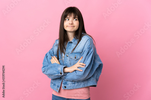 Young Ukrainian woman isolated on pink background making doubts gesture while lifting the shoulders