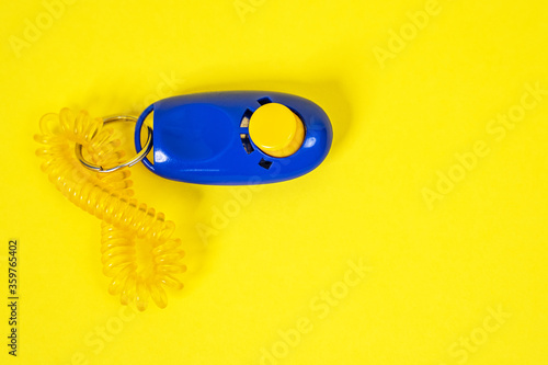 Dog clicker  positive reinforcement training tool for dogs on yellow background. Clicker used for animal training or education photo