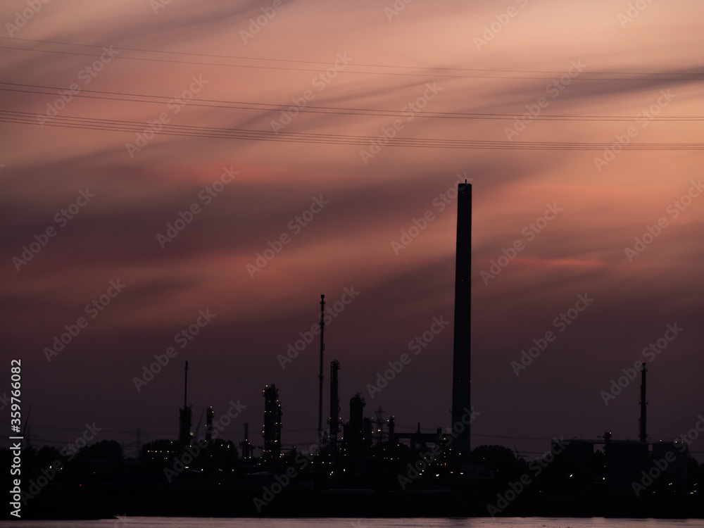 Silhouette of industrial enterprise chimneys in the city on the river bank on a sunset. Silhouette of industrial enterprise chimneys in the city on the river bank on a sunset.