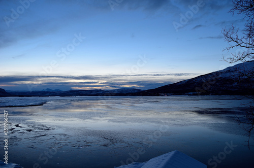 blue frozen fjord and snowy mountain during the blue hour in northern norway