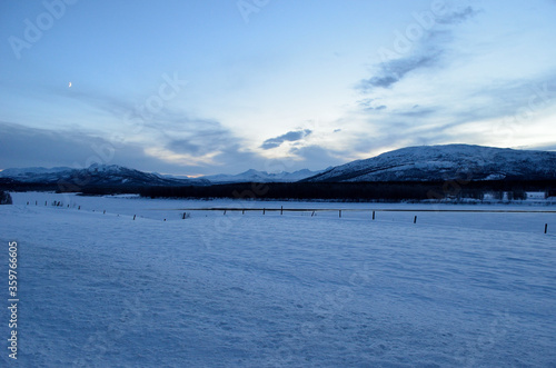 snowy winter pasture with mountain at sunset