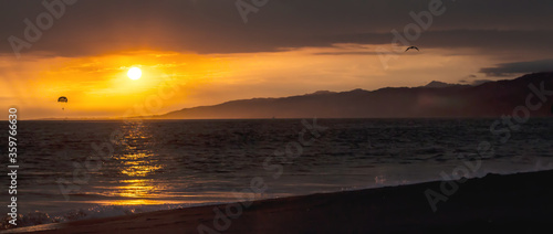 Pacific Ocean by sunset with San Gabriel Mountains in the background