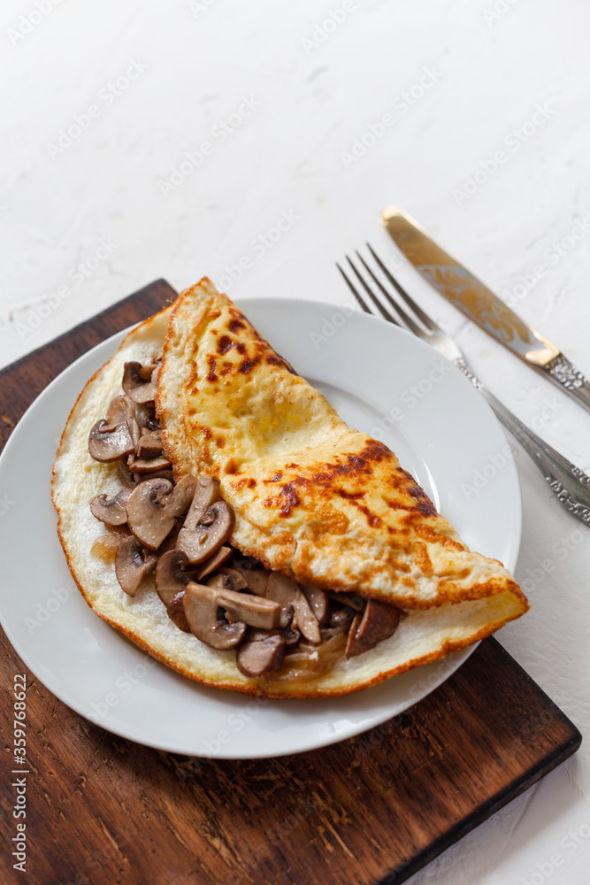 Omelet with mushrooms on a wooden board