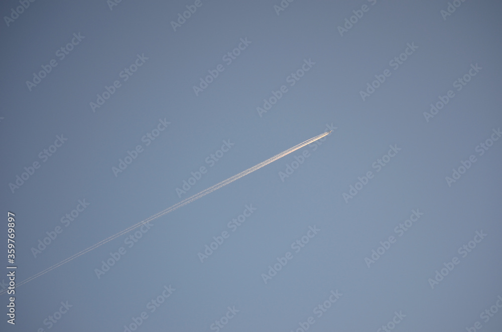 Airplane leaves thick condensation stripe on the clear winter sky Airplane leaves thick condensation stripe on the clear winter sky