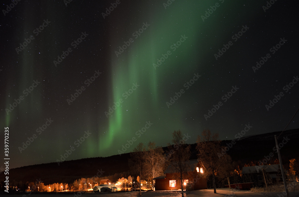 beautiful aurora borealis over houses at christmas time in the arctic circle