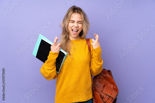 Teenager Russian student girl isolated on purple background with fingers crossing