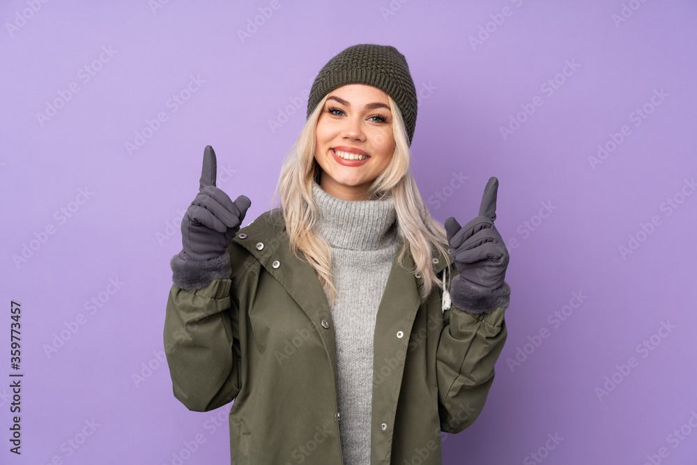 Teenager blonde girl with winter hat over isolated purple background pointing up a great idea Teenager blonde girl with winter hat over isolated purple background pointing up a great idea